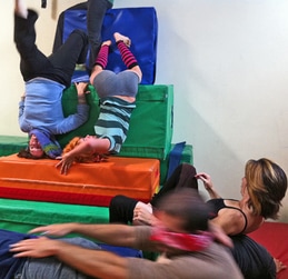 5 dancers on and near a stack of gymnastic blocks. Two are upside down.